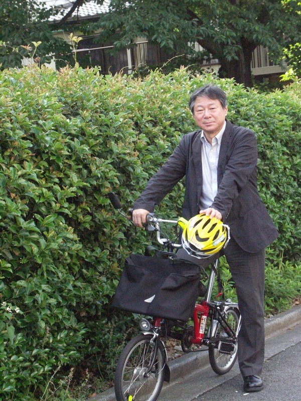 自転車活用推進研究会理事長の小林成基さん。愛車のブロンプトンとともに