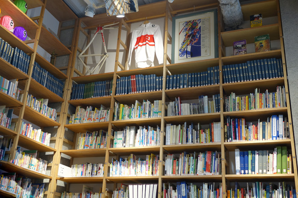 壁一面に並べられた自転車関連の書籍や雑誌。フロアにはクラシックな自転車や部品が展示されている